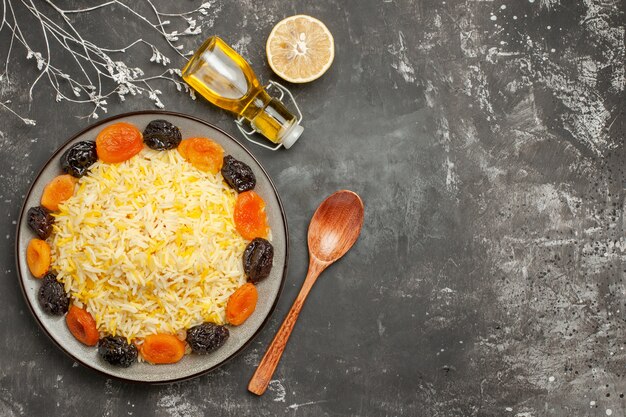 Top close-up view rice plate of rice with dried fruits lemon spoon bottle of oil