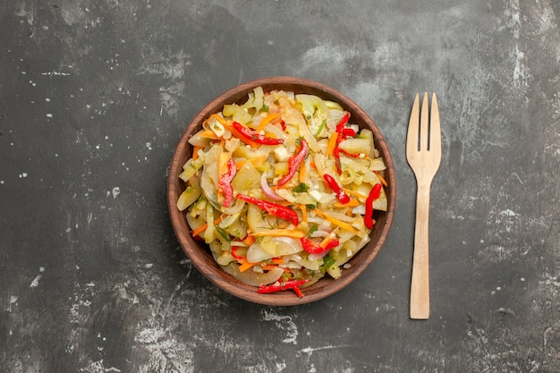 Top close-up view salad bowl of vegetable salad wooden fork on the table