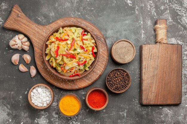 まな板の上のカラフルなスパイス野菜サラダのトップクローズアップビューサラダニンニクボウル