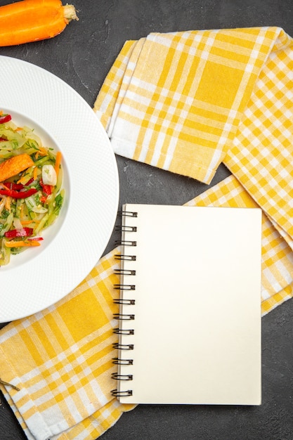 Top close-up view salad plate of salad with vegetables checkered tablecloth notebook