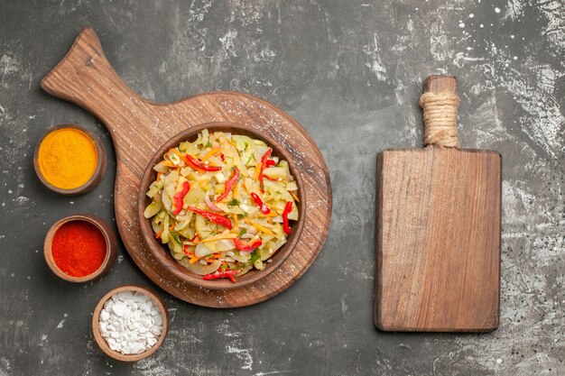 Top close-up view salad spices vegetable salad in the bowl next to the cutting board