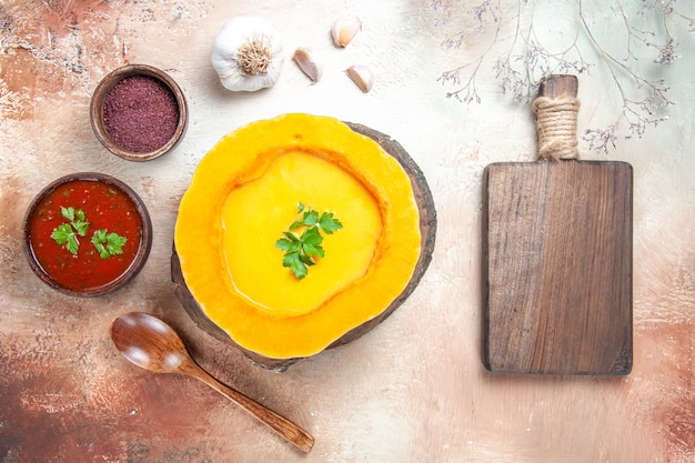 Top close-up view soup garlic spoon sauce spices pumpkin soup next to the cutting board