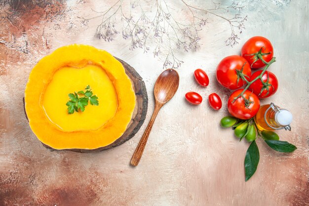 Top close-up view a soup pumpkin soup on the board oil citrus fruits tomatoes spoon