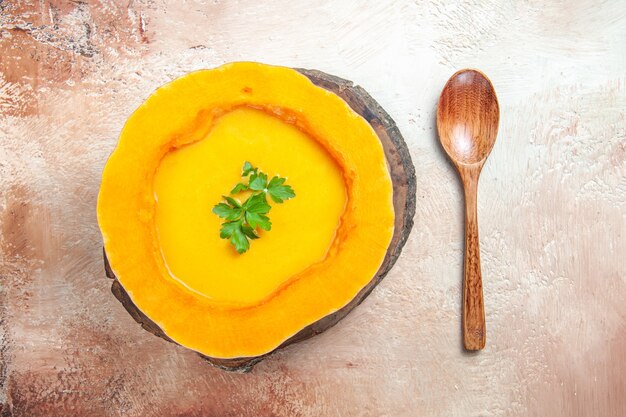 Foto gratuita vista ravvicinata dall'alto una zuppa una zuppa di zucca sul tabellone accanto al cucchiaio