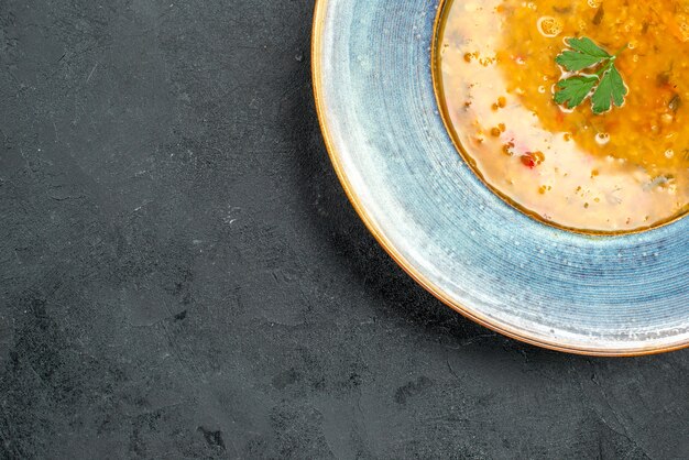 Top close-up view soup soup with herbs in the blue bowl on the table