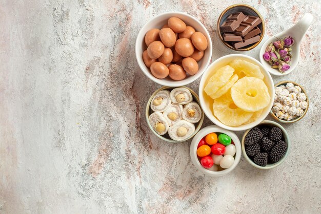 Top close-up view sweets in bowls eight bowls of different sweets and dried fruits and berries on the table