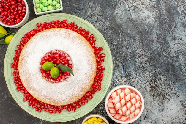 Foto gratuita vista ravvicinata dall'alto dolci una torta con semi di melograno ciotole di caramelle colorate sul tavolo