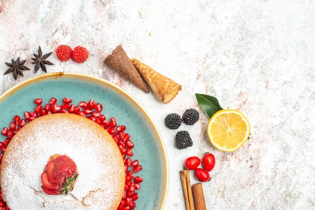 Top close-up view sweets a cake with pomegranate star anise cinnamon sticks berries lemons