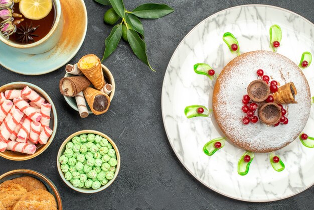 Top close-up view sweets a cup of tea citrus fruits cookies waffles candies cake with berries