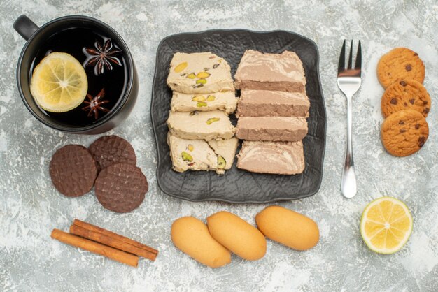 Top close-up view sweets plate of sunflower seed halva cookies cinnamon fork a cup of tea