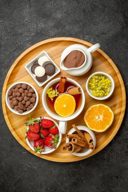 Foto gratuita vista ravvicinata dall'alto dolci sul piatto da tavola di cioccolato fragole limone bastoncini di cannella e una tazza di tè al limone