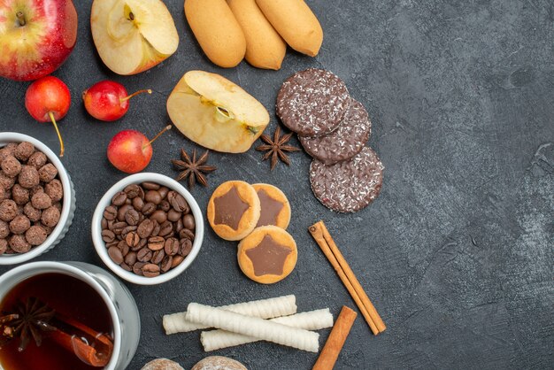 Top close-up view tea a cup of tea cookies nuts coffee beans apples cherries