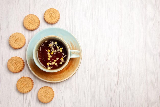 Foto gratuita tè con vista ravvicinata dall'alto con biscotti tazza bianca di tisana accanto ai biscotti sul tavolo bianco