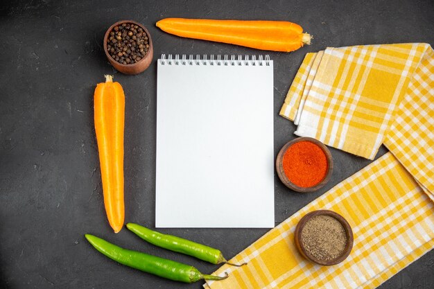 Top close-up view vegetables notebook checkered tablecloth carrots hot peppers spices