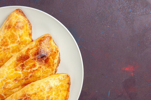 Top close view baked pastries bread like inside plate on dark space