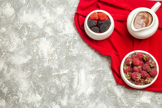 Top close view of berries and chocolate on red napkin with free place for your text on marble background