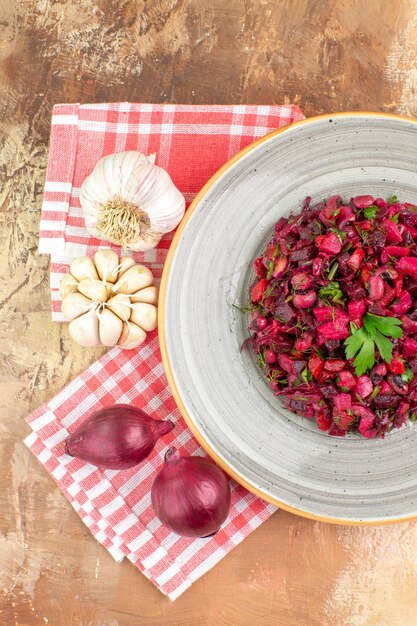 Top close view of bowl of a red salad with greens on it on a wooden backgorund