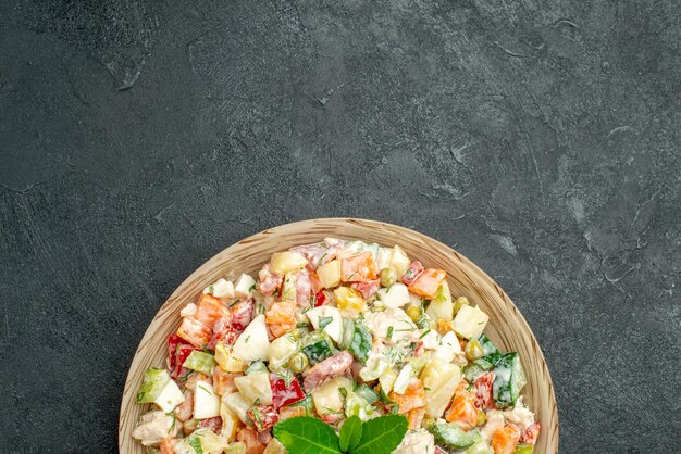 Top close view of bowl of vegetable salad on the bottom side with green on it on dark green background