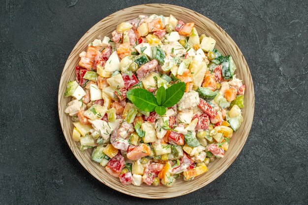 Top close view of bowl of vegetable salad in the center with green on it on dark green background