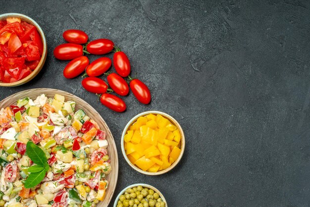 Top close view of bowl of vegetable salad with vegetables on dark grey table