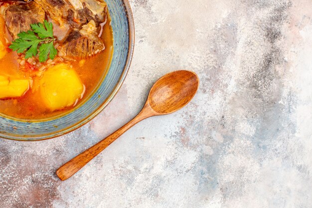 Top close view bozbash soup a wooden spoon on nude background