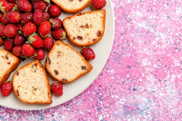 ピンクの壁のケーキに新鮮なイチゴとプレートの内側にレーズンが入ったトップクローズビューケーキスライスは甘いビスケット色のパイシュガークッキーを焼きます