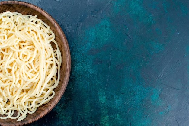 上部のクローズビュー青い壁のパスタイタリア料理ディナー生地肉の丸い木のプレートの内側に調理されたイタリアンパスタ