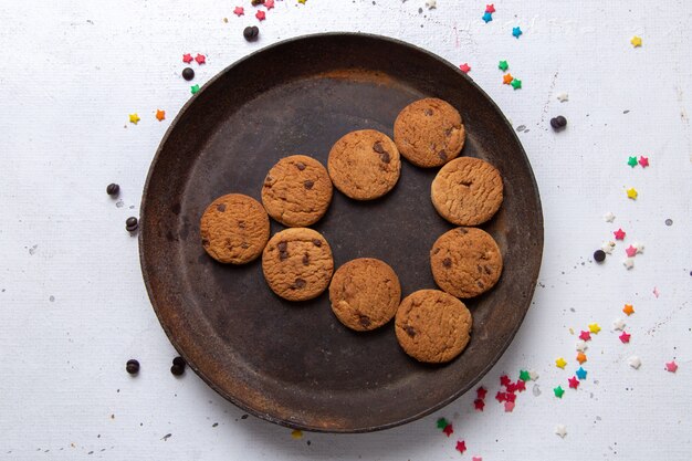 Top close view delicious chocolate cookies inside brown round plate on the white desk cookie biscuit sweet tea