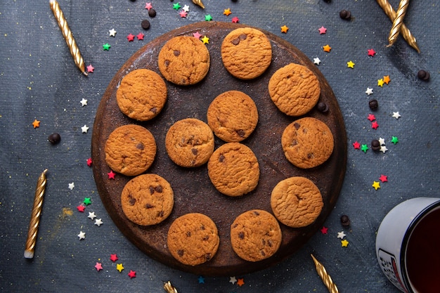 Top vista ravvicinata deliziosi biscotti al cioccolato con candele e tè sullo sfondo scuro biscotto biscotto tè dolce