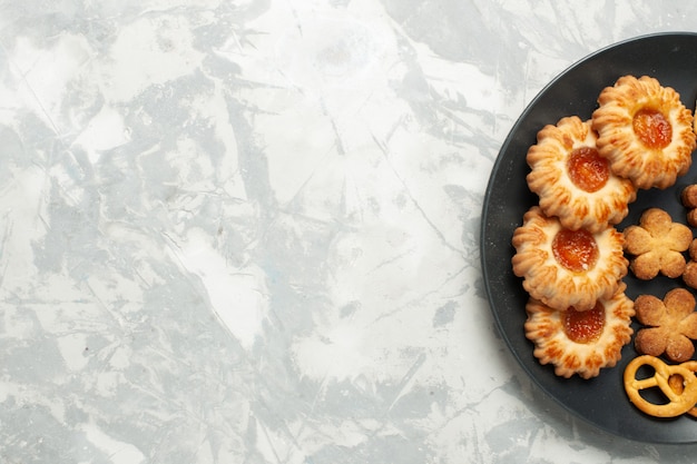 Foto gratuita vista ravvicinata dall'alto deliziosi biscotti con cracker e patatine all'interno del piatto sulla scrivania bianco chiaro