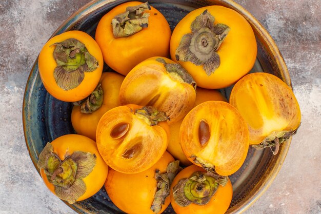 Top close view delicious persimmons in round wood box on nude background