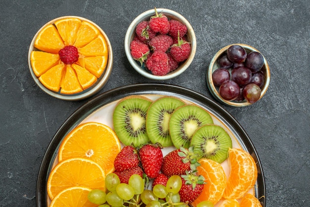 Top close view different fruits composition fresh and sliced fruits on dark background health ripe fresh fruit mellow