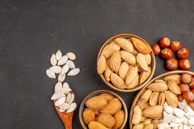 Top close view of different nuts fresh nuts inside pots on dark surface