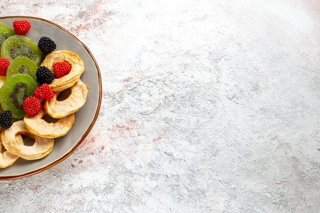 Top close view dried pineapple rings with dried kiwis confitures and apples on white wall fruit dry sweet sugar candy