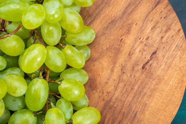 Top close view fresh green grapes mellow juicy fruits on dark-blue desk.