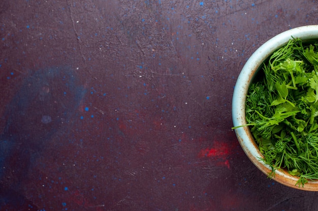 Сверху крупным планом свежая зелень внутри круглой миски на темном столе, свежие зеленые овощи