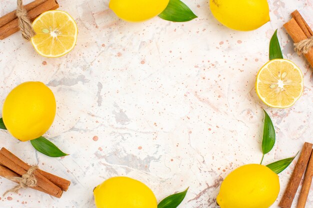 Top close view fresh lemons in a circle shape cut lemons cinnamon sticks on bright isolated background free space