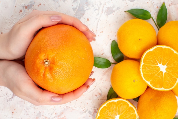 Free photo top close view fresh mandarines cinnamon sticks cut orange in woman hands on bright isolated background