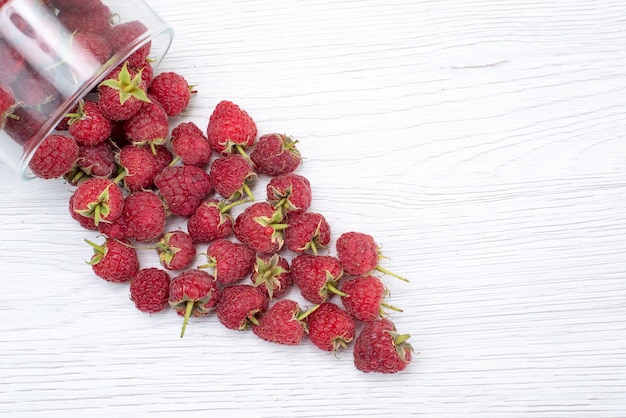 Top close view of fresh red raspberries inside and outside bowl on light , berry fruit fresh color photo