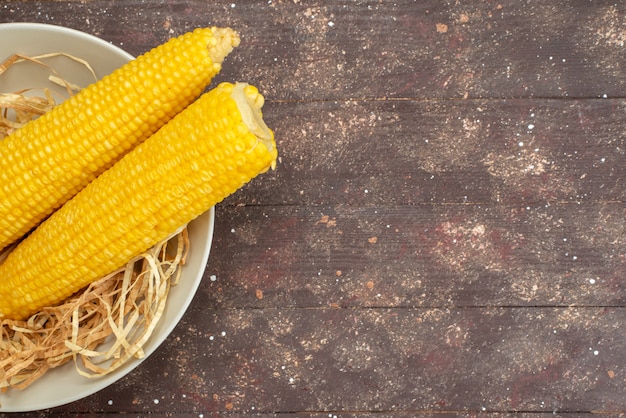 Free photo top close view fresh yellow corns inside white plate on wood, food meal color