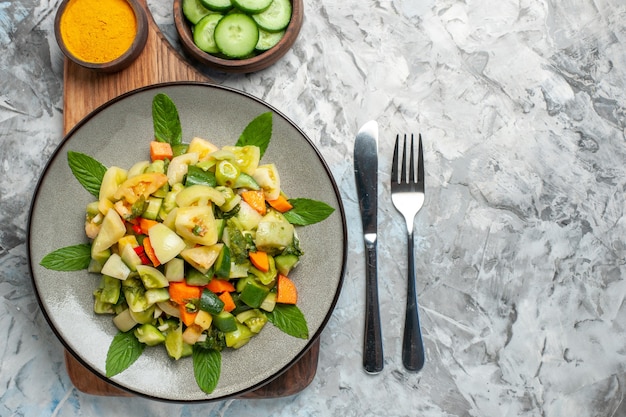 まな板のフォークと暗い背景のナイフの楕円形のプレートにトップクローズビューグリーントマトサラダ