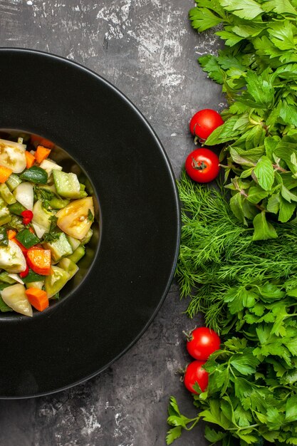 Top close view green tomato salad on oval plate greens tometoes on dark background