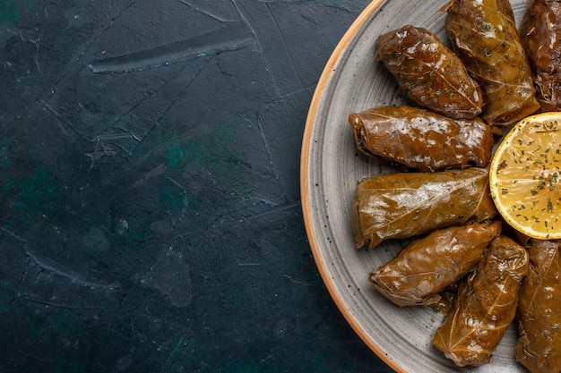 Free photo top close view leaf dolma delicious eastern meat meal rolled inside green leaves on dark blue desk