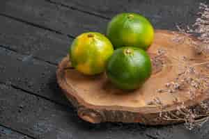Free photo top close view lime on table limes on brown board on the grey table under branches of tree