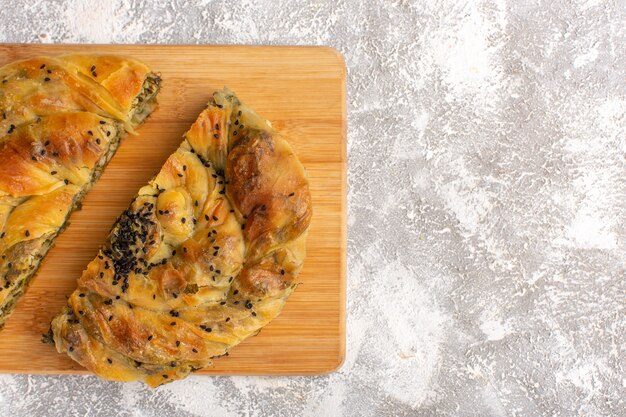 Top close view pastry with meat delicious dough meal sliced on white-light desk.