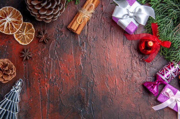 Top close view pine tree branches cones xmas tree toys cinnamon dried lemon slices star anises on dark red background