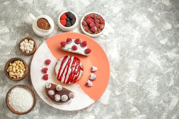 Top close view of plate of sweet with berries flour tea sieve chocolate and nuts on side on marble background