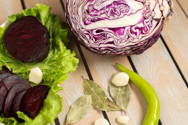 Top close view of purple beet with purple cabbage, green lettuce and garlic on the wooden desk