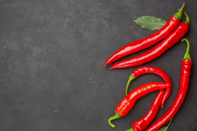 Top close view red peppers and pay leaves at the right side of black table with free space