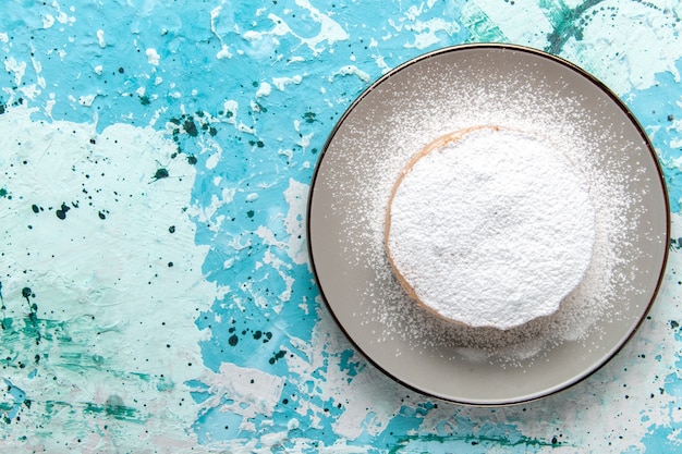 Top close view round cake with sugar powder inside plate on light-blue surface cake bake biscuit sugar sweet tea color